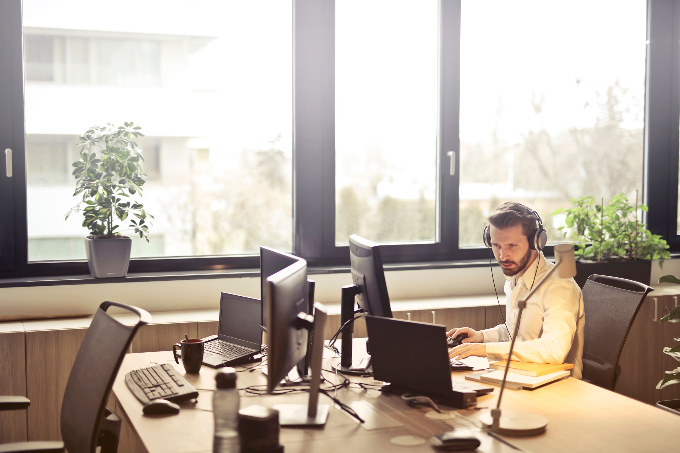 Technicien de soutien TI au casque, au travail devant ses écrans dans un bureau lumineux